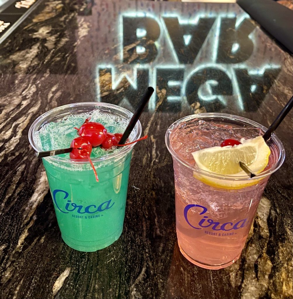 Two branded Circa Resort and Casino drinks: one blue and one pink with lemons and cherries 