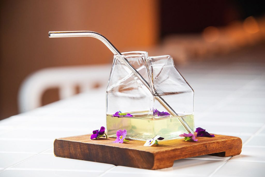 Mixed drink with violets surrounded drink on a wooden holder