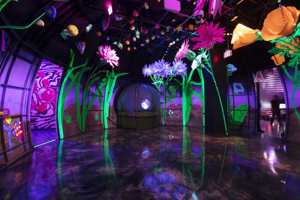 art installation of life size flowers in Omega Mart in Area 15 by Meow Wolf