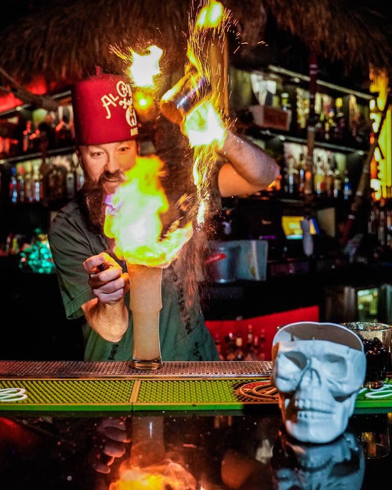 Golden Tiki bartender serving flaming adult drink at bar
