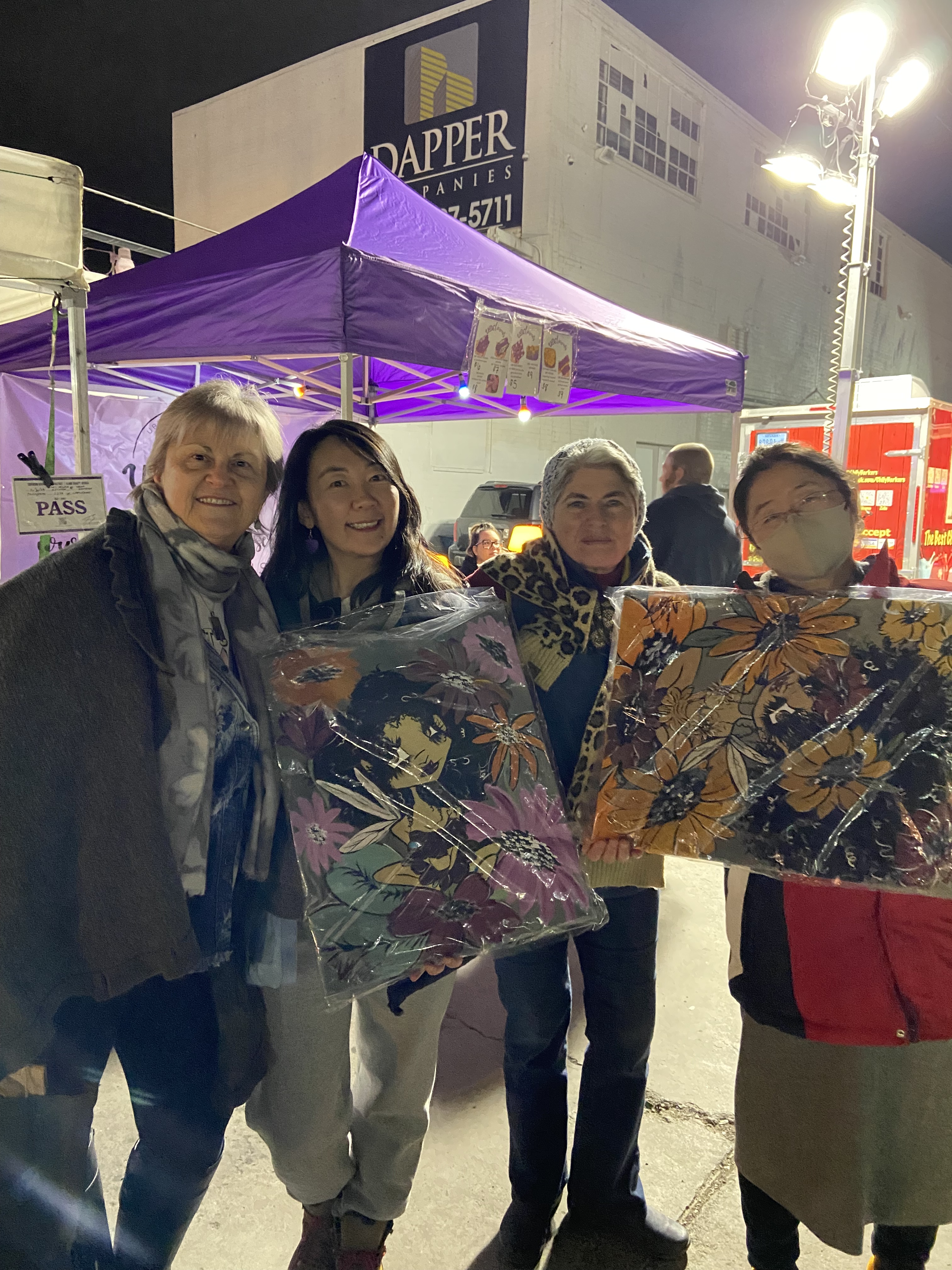 First Friday February 2023 festival goers Michelle and Mia with friends and family holding art they bought from local artists.