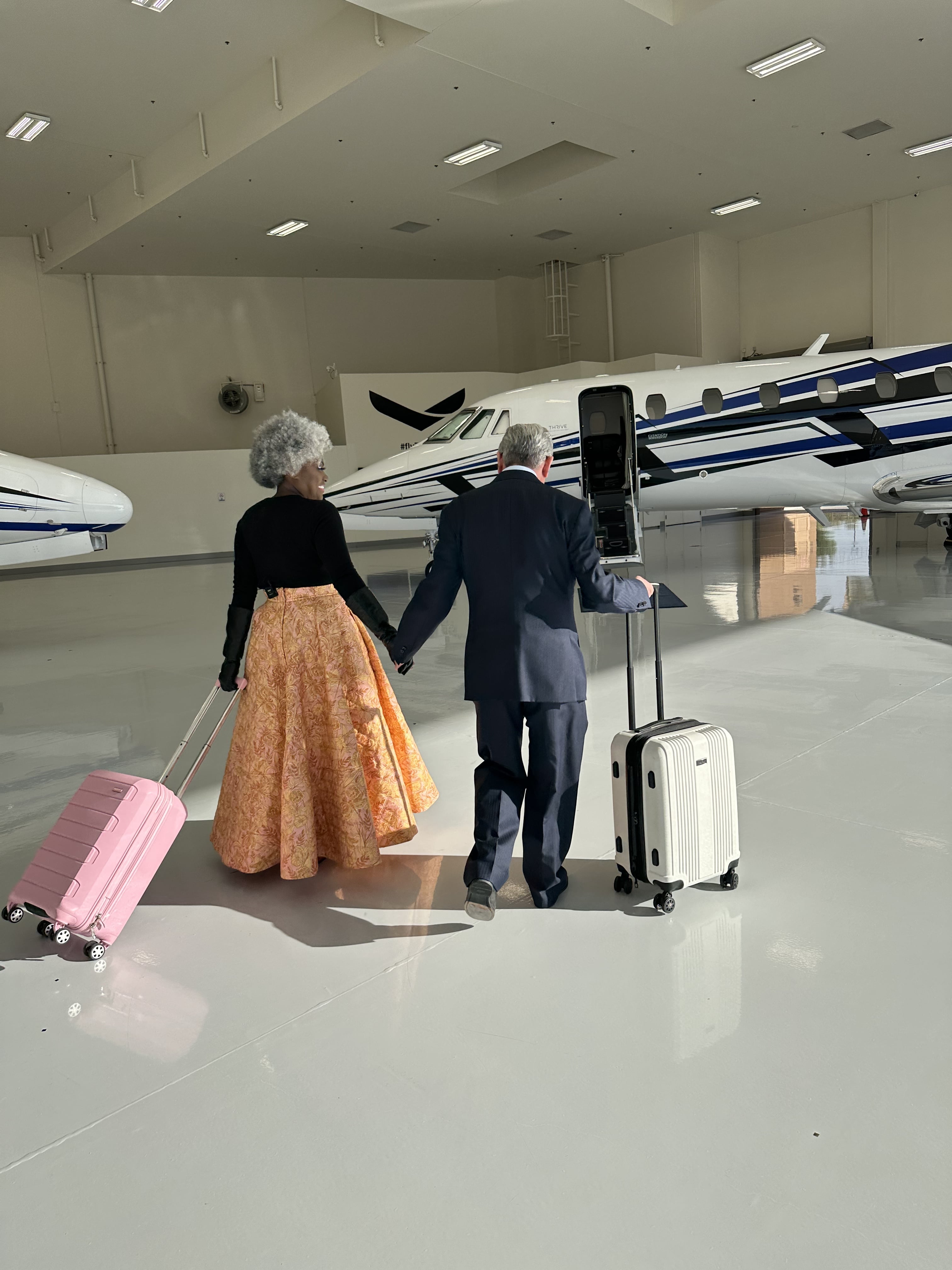 Couple leaving with luggage in middle of Thrive Aviation Private Jet Hangar - promotional photo for Miracle Flights SOARèe