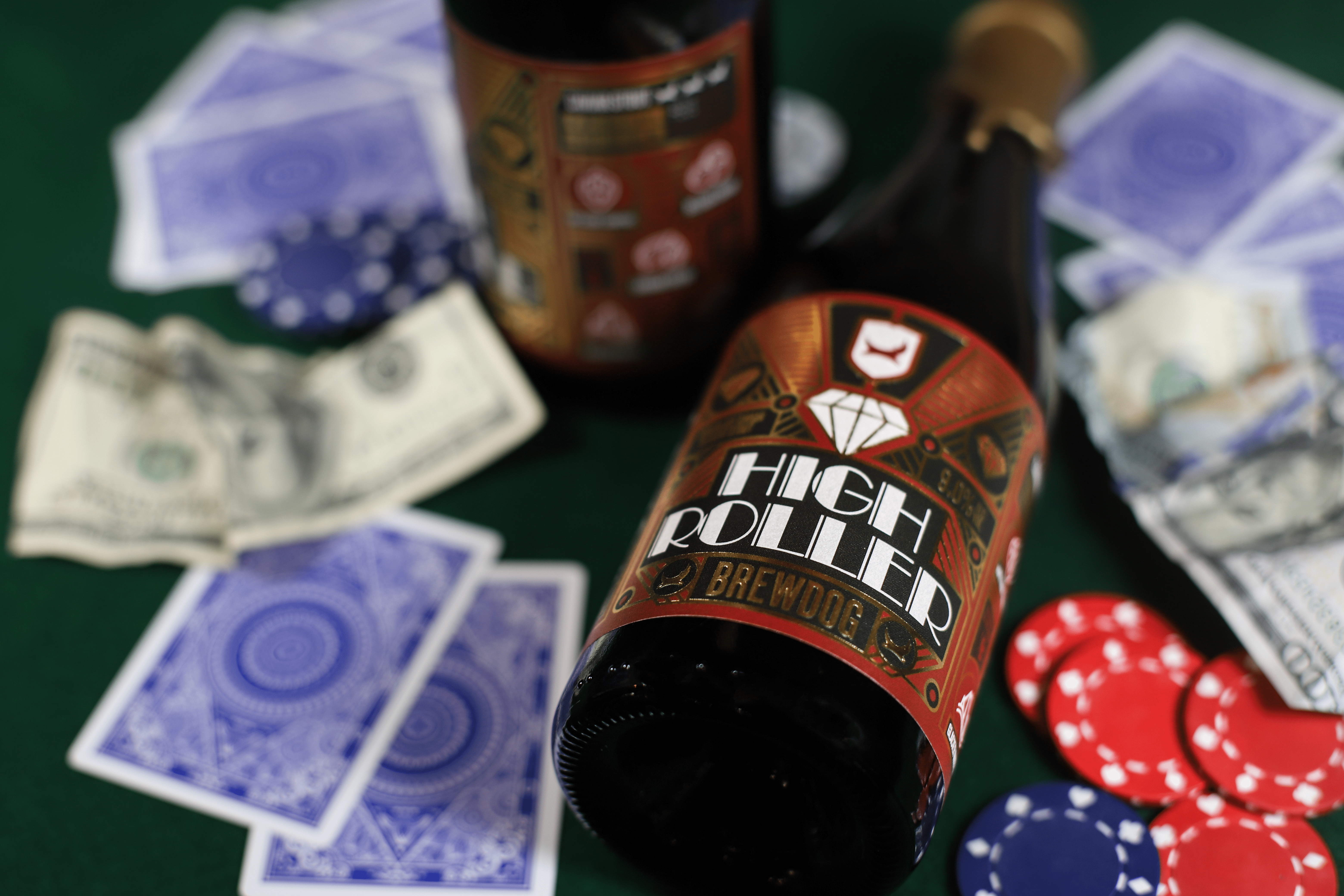 High-Roller beer bottle lying on poker table with cards and chips